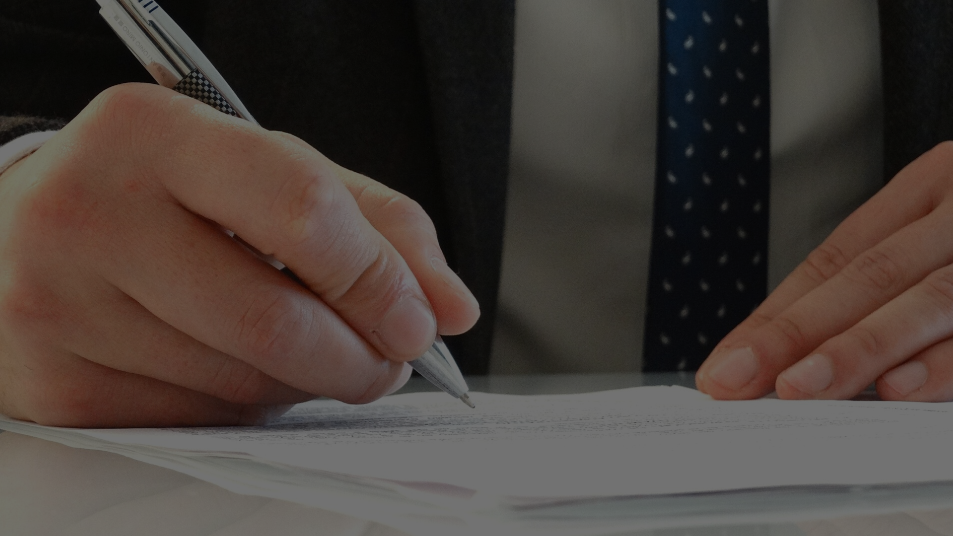 Person in a business suit signing a leasing document.